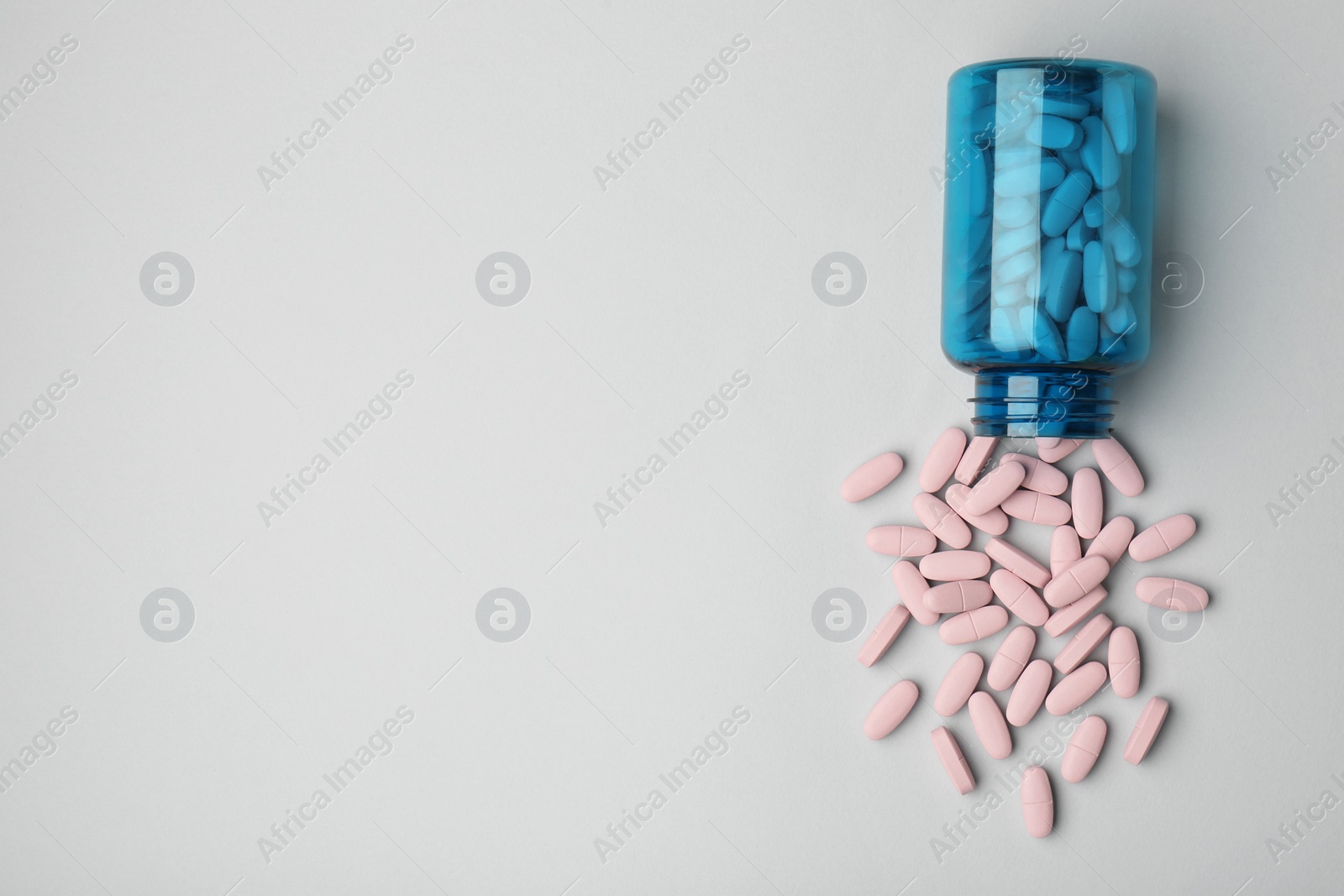 Photo of Vitamin pills and bottle on grey background, top view. Space for text