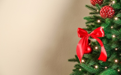 Decorated Christmas tree on beige background, closeup. Space for text