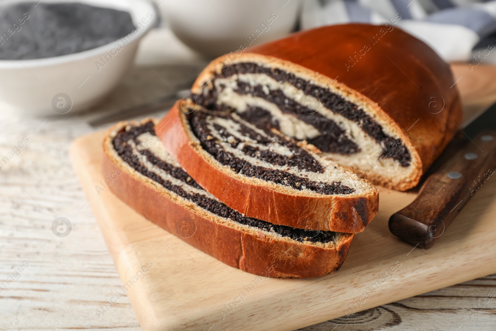 Photo of Cut tasty sweet bun with poppy seeds on wooden table