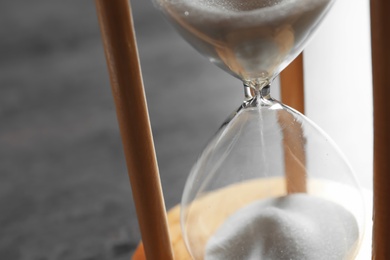 Photo of Hourglass with flowing sand on table, closeup. Time management