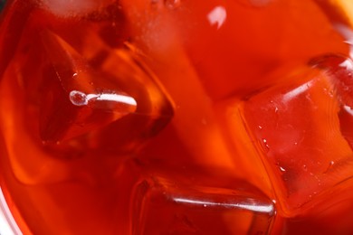 Photo of Tasty Aperol spritz cocktail with ice cubes as background, closeup