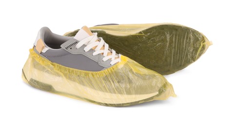 Photo of Men's sneakers in yellow shoe covers isolated on white