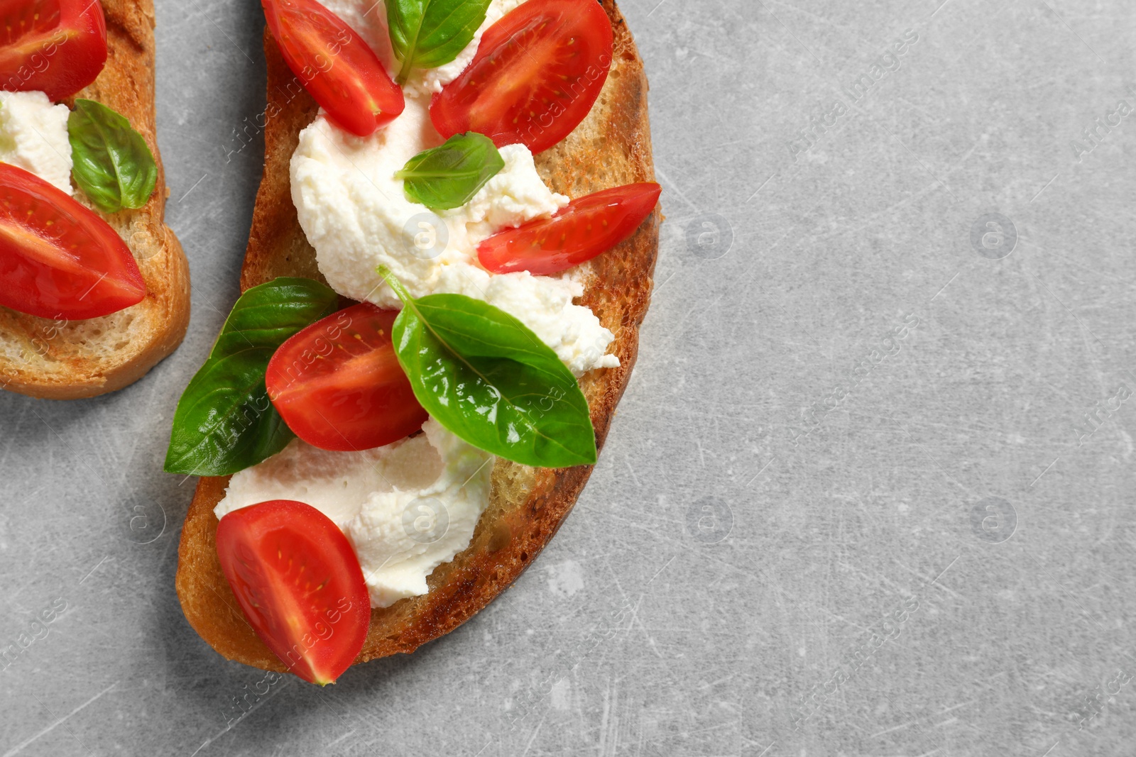 Photo of Toasted bread with tasty cream cheese and tomatoes on gray background, flat lay. Space for text