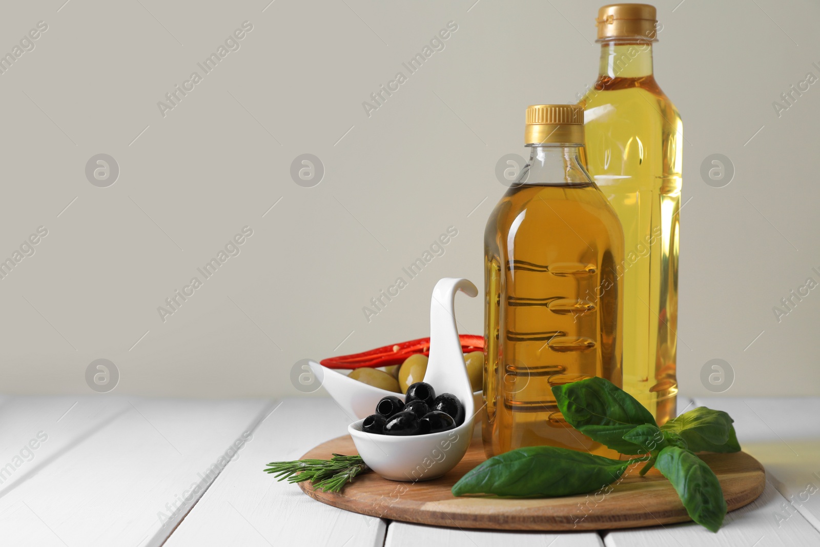 Photo of Different cooking oils and ingredients on white wooden table against light background, space for text