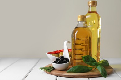Photo of Different cooking oils and ingredients on white wooden table against light background, space for text