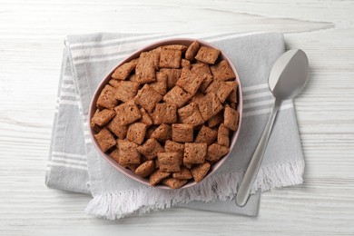 Sweet crispy corn pads in bowl and spoon on white wooden table, flat lay