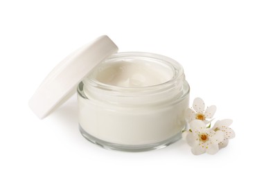 Face cream in glass jar and flowers on white background