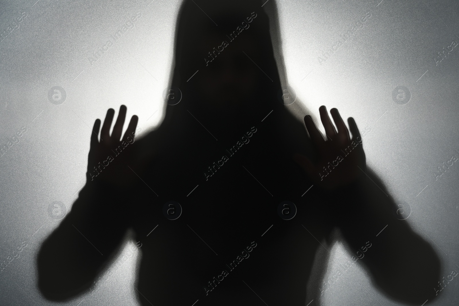 Photo of Silhouette of ghost behind glass against grey background