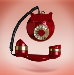 Image of Vintage red corded telephone flying in air on color background