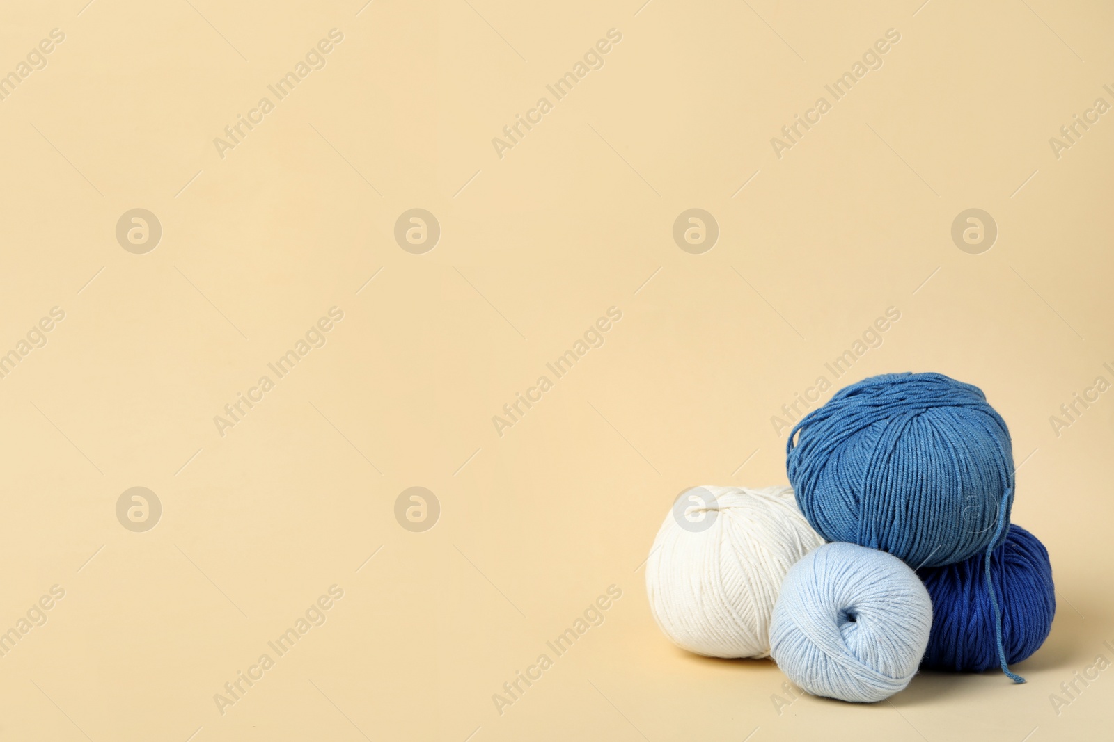 Photo of Soft woolen yarns on beige background, space for text