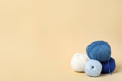 Photo of Soft woolen yarns on beige background, space for text
