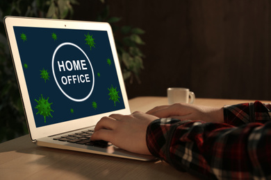 Woman working with laptop at wooden table, closeup. Home office