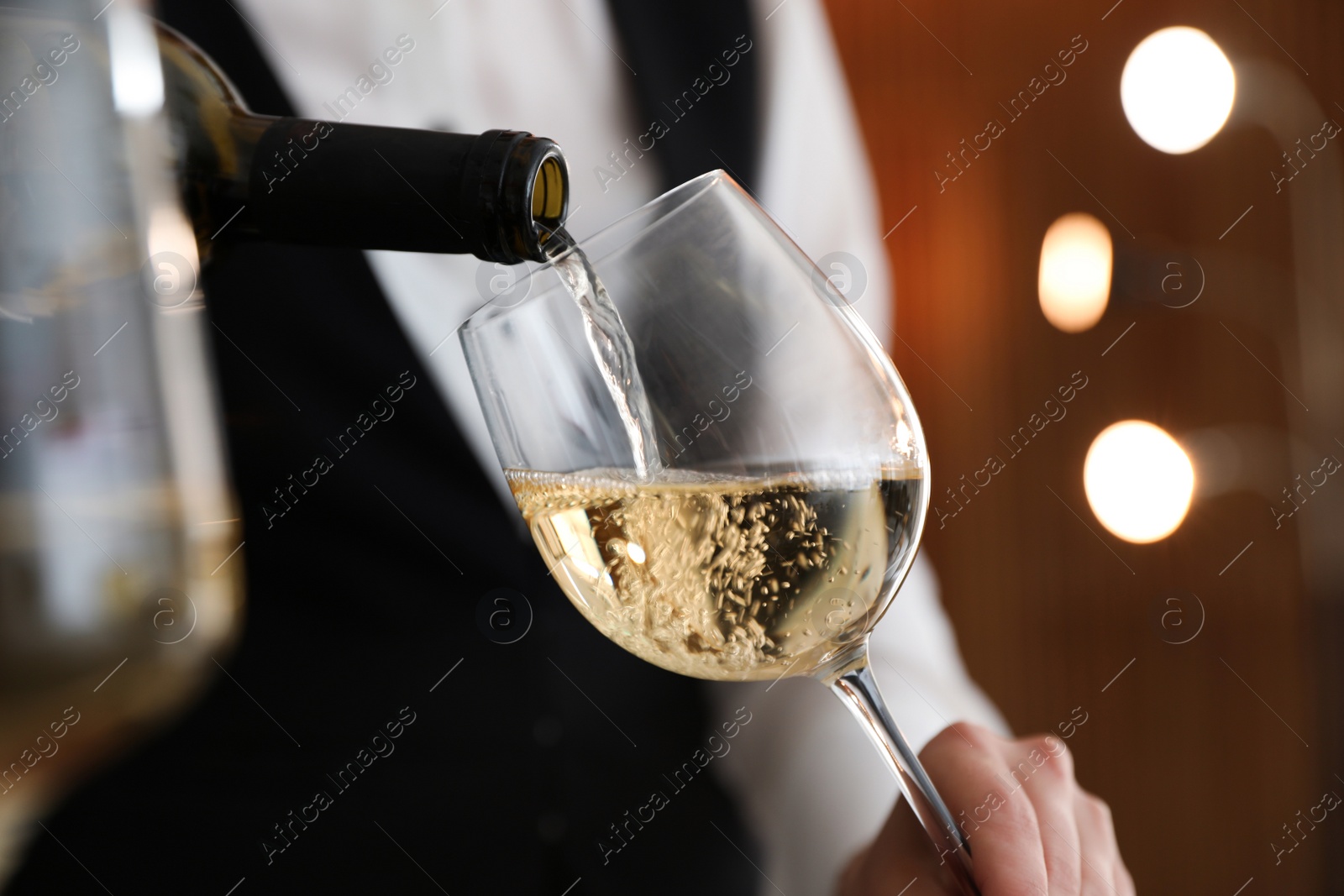 Photo of Waitress pouring wine into glass in restaurant, closeup