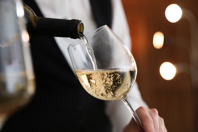 Waitress pouring wine into glass in restaurant, closeup