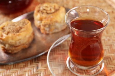 Traditional Turkish tea in glass on wicker table, closeup. Space for text