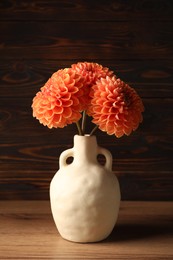 Beautiful flowers in vase on wooden table