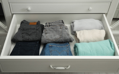 Photo of Folded clothes in open drawer. Apparel storage