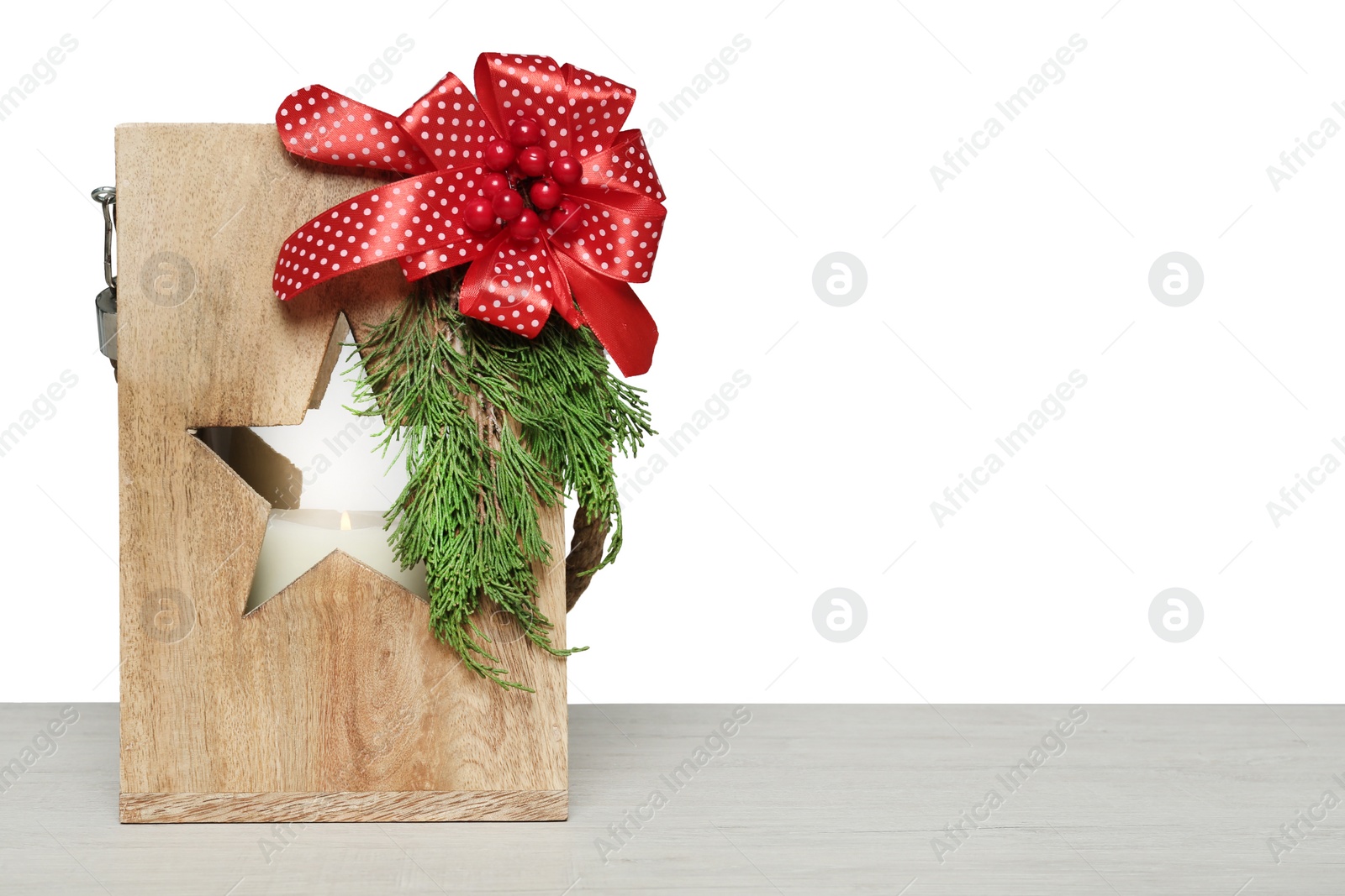 Photo of Wooden Christmas lantern with burning candle on table. Space for text