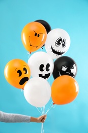 Photo of Woman holding color balloons for Halloween party on blue background, closeup