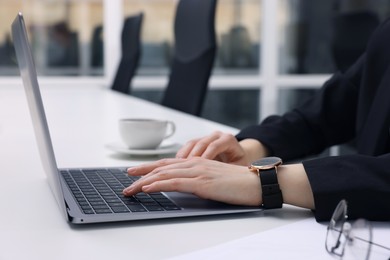 Photo of Woman working with laptop at white desk in office, closeup