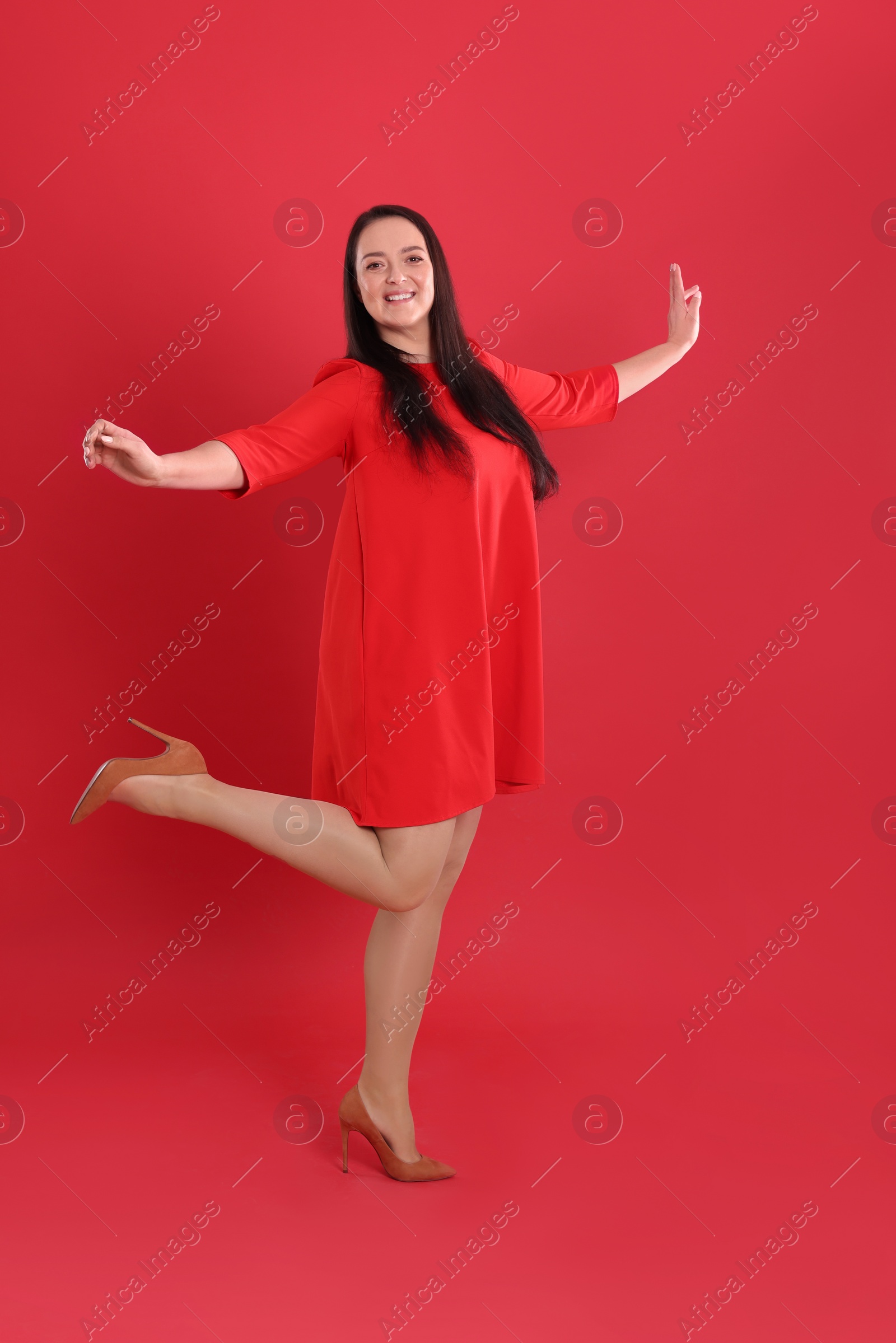 Photo of Beautiful overweight woman in dress on red background