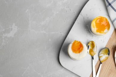 Photo of Soft and medium boiled chicken eggs on light grey marble table, flat lay. Space for text