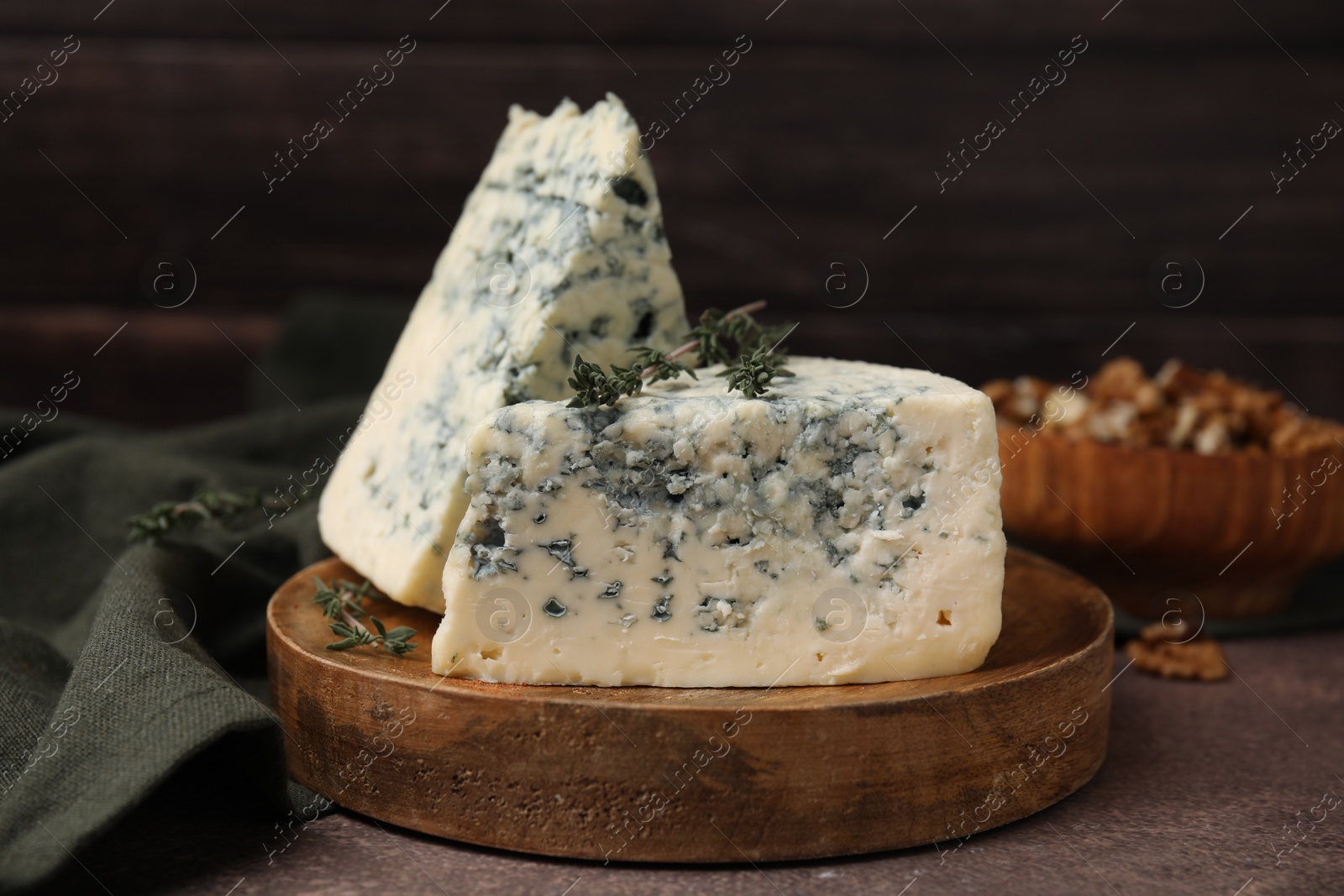 Photo of Tasty blue cheese with thyme on brown table