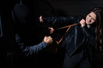 Photo of Woman fighting with thief while he trying to steal her bag near car at night. Self defense concept