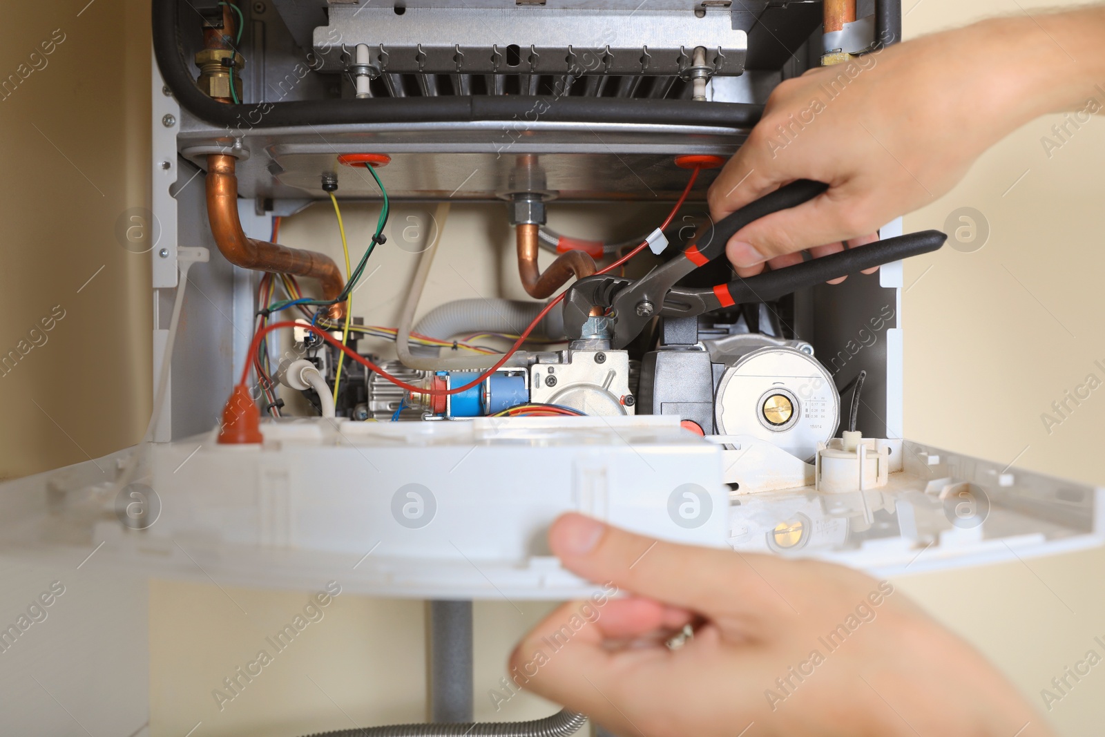 Photo of Man repairing gas boiler with waterpump plier, closeup