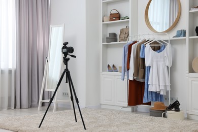 Fashion blogger's workplace. Shoes, clothes, camera and stylish furniture indoors