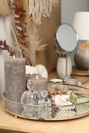 Photo of Perfumes and burning candles on wooden makeup table in room