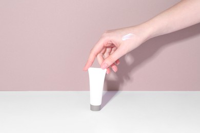 Photo of Woman with tube of cream on color background, closeup