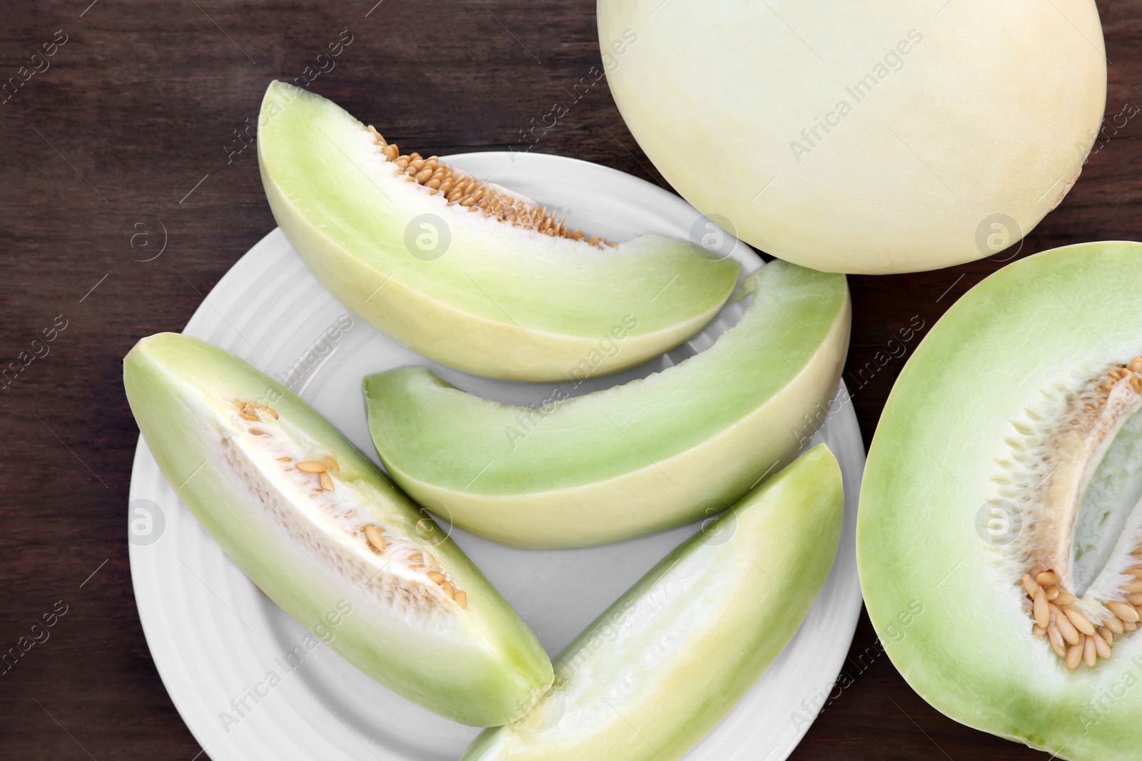 Photo of Tasty whole and cut ripe melons on wooden table, flat lay