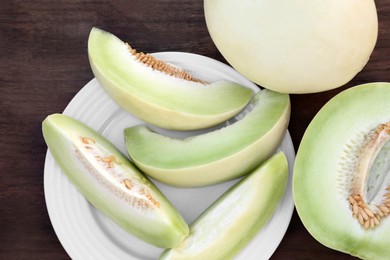 Tasty whole and cut ripe melons on wooden table, flat lay