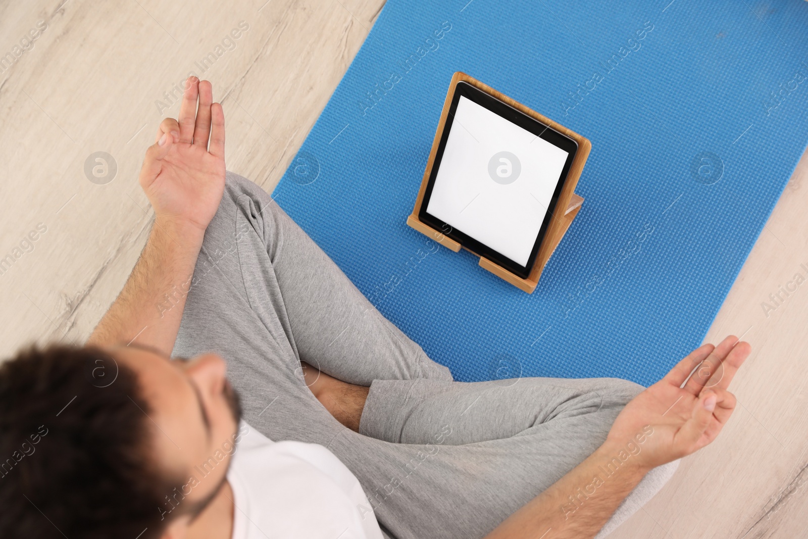 Photo of Man practicing yoga while watching online class at home during coronavirus pandemic, above view. Social distancing