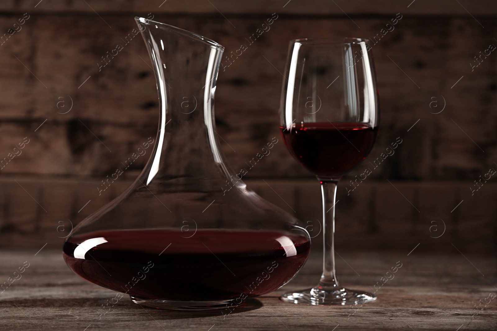 Photo of Elegant decanter and glass with red wine on wooden table