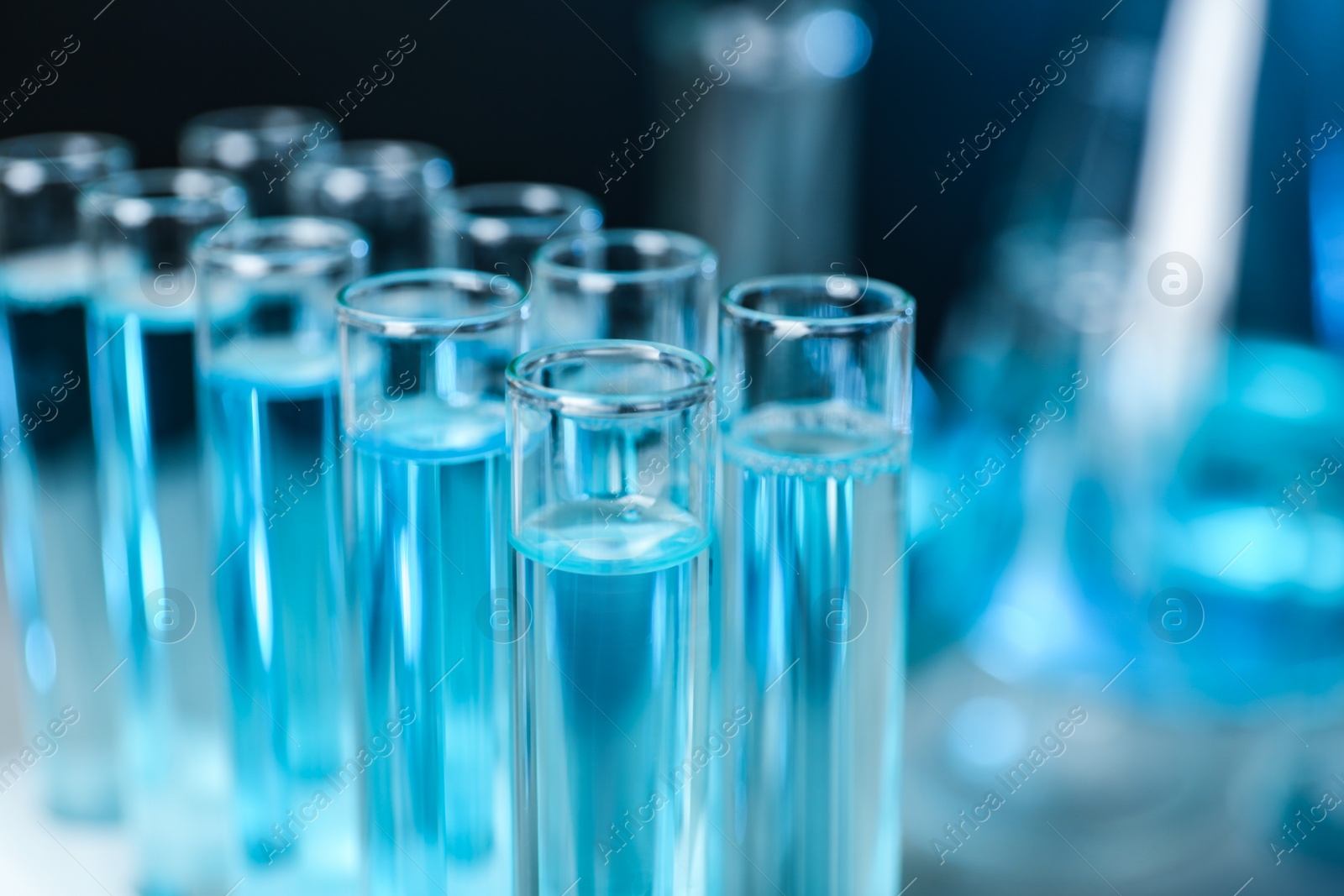 Photo of Test tubes with liquid on blurred background, closeup with space for text. Solution chemistry