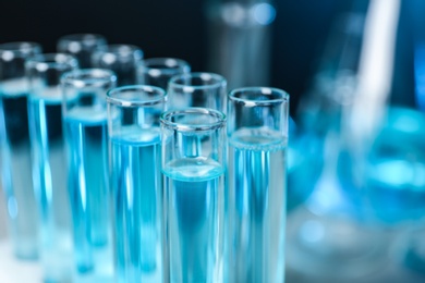 Photo of Test tubes with liquid on blurred background, closeup with space for text. Solution chemistry