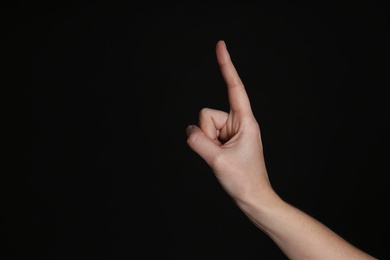 Photo of Woman pointing at something on black background, closeup. Finger gesture