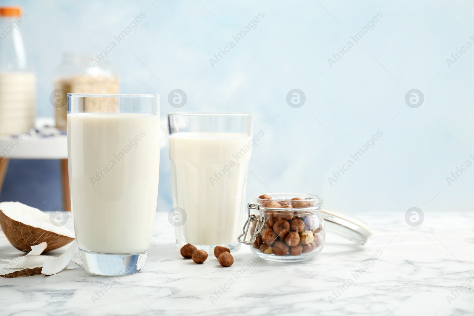 Photo of Glasses with milk substitute and nuts on kitchen table