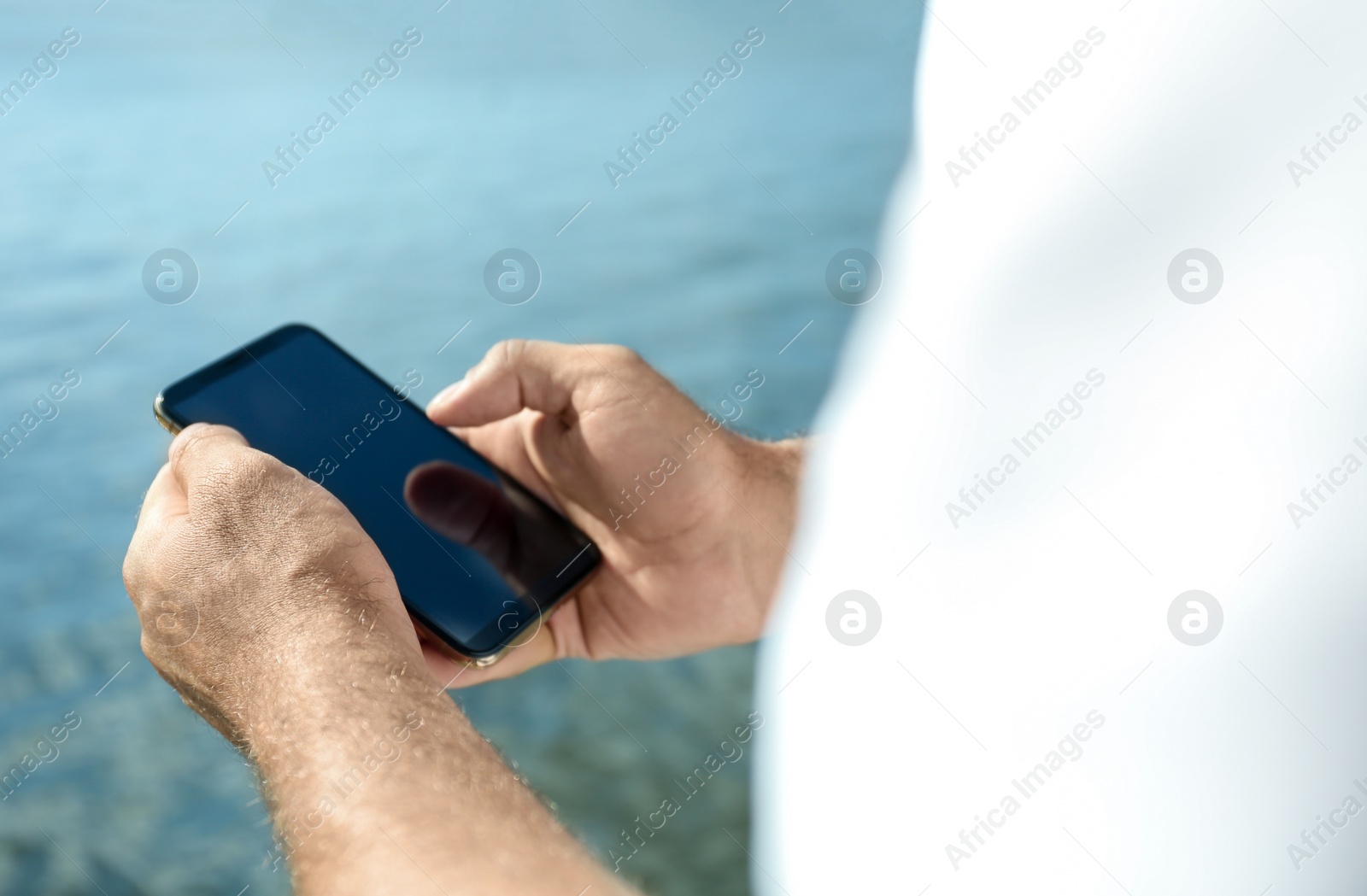 Photo of Man using modern mobile phone near river, closeup