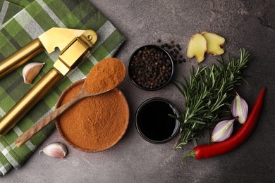 Photo of Aromatic spices, fresh ingredients for marinade and garlic press on brown table, flat lay