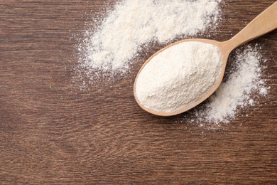 Photo of Spoon with quinoa flour on wooden table, top view. Space for text