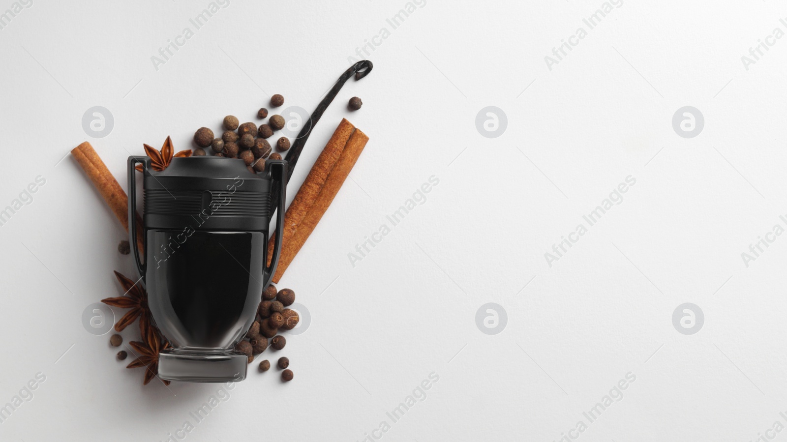 Photo of Bottle of perfume surrounded by different spices on white background, top view. Space for text