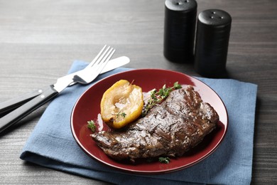 Photo of Delicious roasted beef meat, caramelized pear and thyme served on grey wooden table