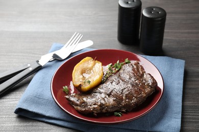 Delicious roasted beef meat, caramelized pear and thyme served on grey wooden table