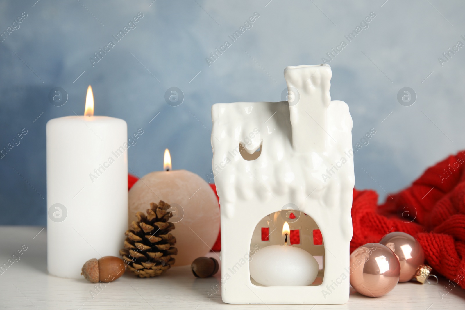 Photo of Composition with candle in house shaped holder on white wooden table. Christmas decoration
