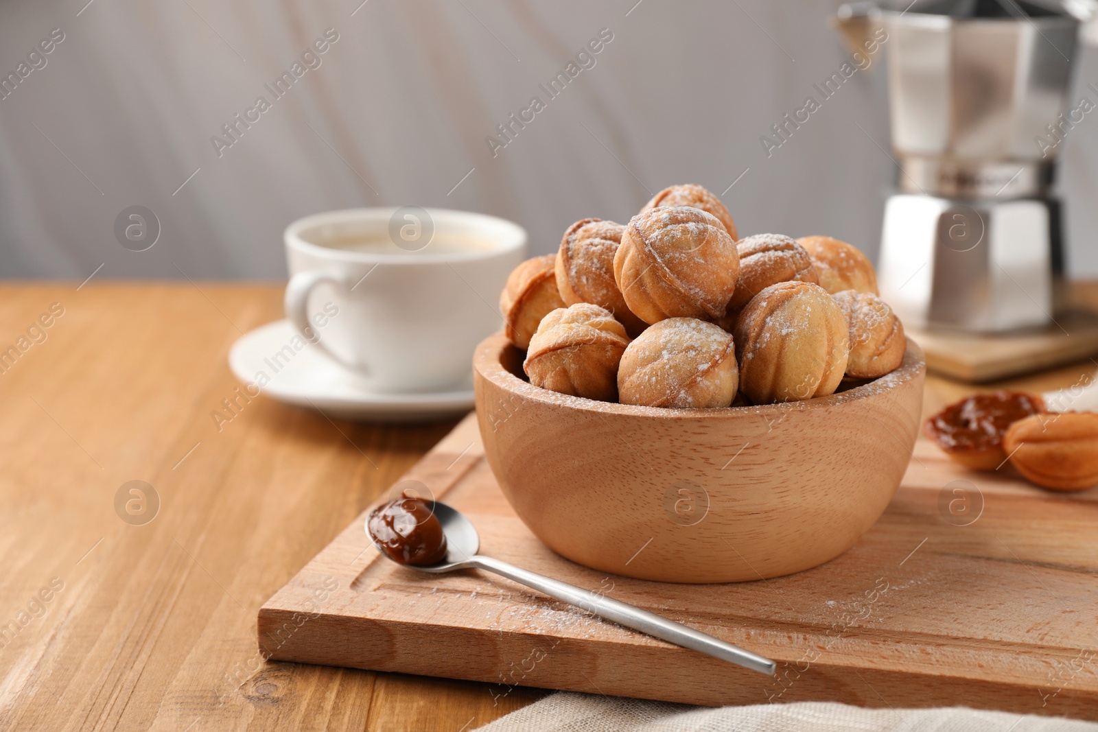 Photo of Bowl of delicious nut shaped cookies with boiled condensed milk on wooden table. Space for text