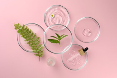 Petri dishes with different plants and cosmetic products on pink background, flat lay
