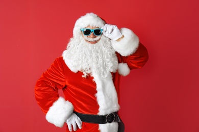 Photo of Authentic Santa Claus wearing sunglasses on color background